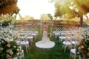 a woman in a wedding dress standing in front of a aisle with chairs at The Inverness Denver, a Hilton Golf & Spa Resort in Englewood