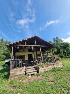 - un petit bâtiment avec une terrasse couverte et des escaliers dans un champ dans l'établissement Bears House, à Furano