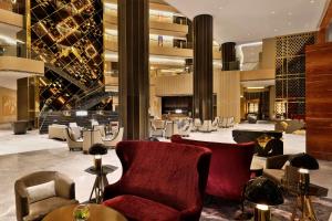 a lobby of a hotel with chairs and a staircase at AlRayyan Hotel Doha, Curio Collection by Hilton in Doha