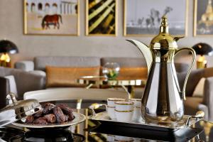 a plate of food on a table with a tea kettle at AlRayyan Hotel Doha, Curio Collection by Hilton in Doha