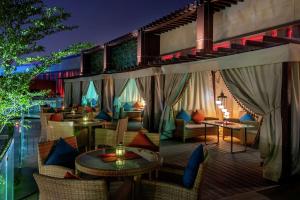 um resort com uma varanda com mesas e cadeiras em AlRayyan Hotel Doha, Curio Collection by Hilton em Doha