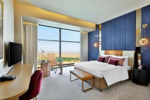 ドーハにあるAlRayyan Hotel Doha, Curio Collection by Hiltonのベッド、デスク、コンピュータが備わる客室です。