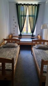 a room with two beds and a window with curtains at Green Cat Rooms in Kraków