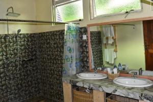 Kisoro的住宿－Bwindi Orugano Lodge，一间带两个盥洗盆和淋浴的浴室