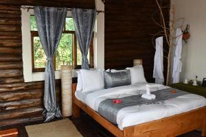 Kisoro的住宿－Bwindi Orugano Lodge，一间卧室设有一张大床和窗户