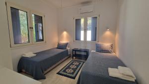 Dos camas en una habitación con dos ventanas. en Blue Gem Villa, en Lefkada