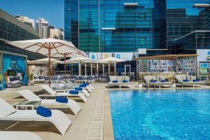 a pool with chairs and umbrellas on a building at DoubleTree by Hilton Dubai - Business Bay in Dubai