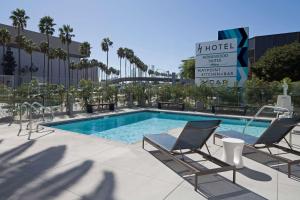 a swimming pool with two chairs and a hotel sign at H Hotel Los Angeles, Curio Collection By Hilton in Los Angeles