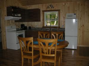 a kitchen with a table and chairs and a white refrigerator at Chalet des Noisetiers in Tadoussac