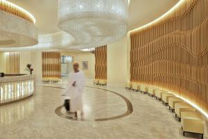 Una mujer caminando por un vestíbulo con una lámpara de araña en Hilton Makkah Convention Hotel en Makkah