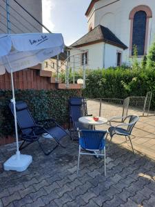 patio z krzesłami, stołem i parasolem w obiekcie Enscher Stübchen Ferienwohnung Rudolf w mieście Ensch