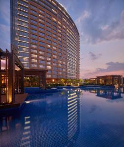 a large building with a swimming pool in front of it at Conrad Bengaluru in Bangalore