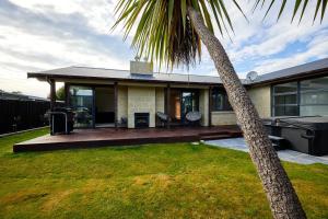 a house with a porch and a palm tree at Whanau Retreat in Kaikoura