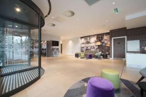 un gran vestíbulo con taburetes morados y verdes en Hampton By Hilton Edinburgh West End, en Edimburgo