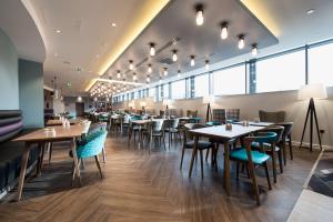 un restaurante con mesas, sillas y ventanas en Hampton By Hilton Edinburgh West End en Edimburgo
