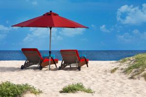 two chairs and an umbrella on the beach at Hilton Cabo Verde Sal Resort in Santa Maria