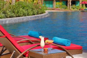 a table with a drink and two chairs next to a pool at Hilton Cabo Verde Sal Resort in Santa Maria