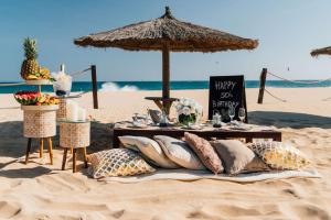 a table with pillows on a beach with an umbrella at Hilton Cabo Verde Sal Resort in Santa Maria