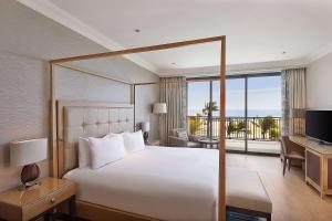 a bedroom with a large bed and a desk with a television at Hilton Cabo Verde Sal Resort in Santa Maria
