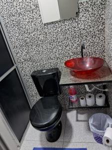 La salle de bains est pourvue de toilettes noires et d'un lavabo. dans l'établissement Alvorada Suite, à Manaus