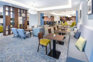 a waiting room with tables and chairs and a library at Hampton By Hilton Gdansk Oliwa in Gdańsk