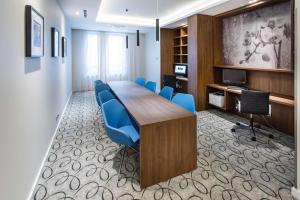 uma sala de conferências com uma mesa de madeira e cadeiras azuis em Hampton By Hilton Gdansk Oliwa em Gdańsk