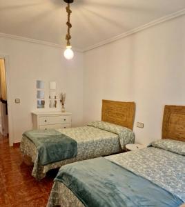 a bedroom with two beds and a light fixture at Piso en Jarandilla de la Vera in Jarandilla de la Vera