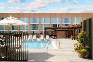 a pool with an umbrella next to a building at Hilton Washington DC National Mall The Wharf in Washington