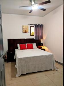 a bedroom with a bed with red pillows and a ceiling fan at Este Hotel in Estelí