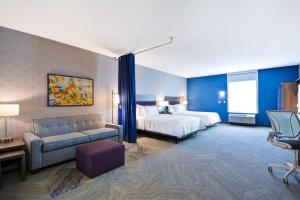 普莱诺Home2 Suites By Hilton Plano Richardson的配有床和沙发的酒店房间