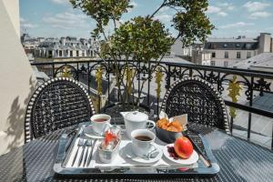uma mesa com uma bandeja de comida e café na varanda em Maison Astor Paris, Curio Collection by Hilton em Paris