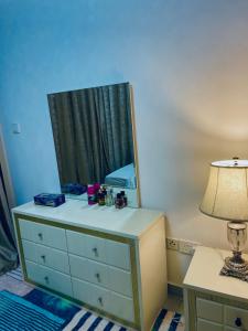 a bedroom with a dresser with a mirror and a lamp at Ayo’s apartment in Dubai