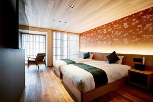a bedroom with two beds and a chair in it at Kikokutei Bekkan in Kyoto