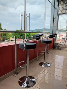 a bar with two stools in front of a window at Este Hotel in Estelí
