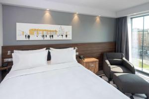 um quarto de hotel com uma cama e uma cadeira em Hampton By Hilton Poznan Old Town em Poznań