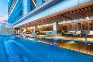 スラバヤにあるDoubleTree by Hilton Surabayaのスイミングプール(椅子付)と建物