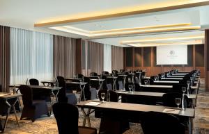 a conference room with tables and chairs and a screen at DoubleTree by Hilton Surabaya in Surabaya