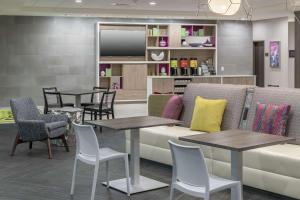 uma sala de espera com um sofá, mesas e cadeiras em Home2 Suites By Hilton Orlando Airport em Orlando