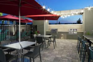 a restaurant with tables and chairs and red umbrellas at Home2 Suites By Hilton Orlando Airport in Orlando