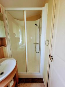 uma casa de banho com um chuveiro e um lavatório. em Lyons Robin Hood Holiday Park, The Shamrock Way em Meliden