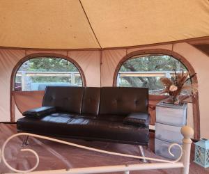a leather couch in a tent with two windows at Al's Hideaway Glamping Tents in Pipe Creek