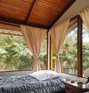 a bedroom with a bed and a large window at Senz Chalet Riverside - Mindo in Mindo