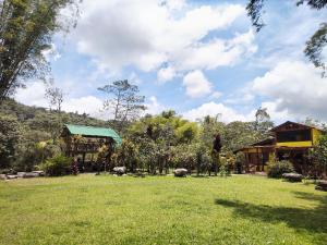 a large yard with a house and a grass field at Senz Chalet Riverside - Mindo in Mindo