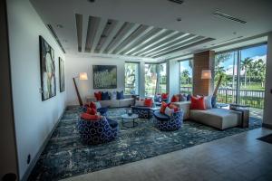 a living room with couches and chairs and windows at Hilton Garden Inn West Palm Beach I95 Outlets in West Palm Beach