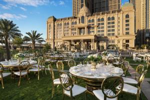 un grupo de mesas y sillas frente a un edificio en Al Habtoor Palace Dubai, en Dubái