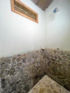a bathroom with a stone wall with a light on it at Tayrona Cachaco River Ecohostal in El Zaino