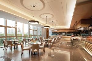 a restaurant with tables and chairs and windows at Doubletree By Hilton Suzhou Wujiang in Suzhou