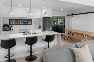 een keuken en een woonkamer met een bank en een tafel bij Decked out on Leo in Waihi Beach