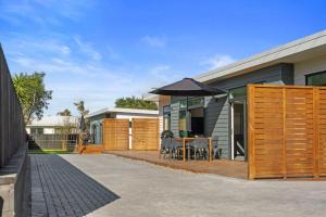 uma casa com um deque de madeira com uma mesa e um guarda-chuva em Decked out on Leo em Waihi Beach