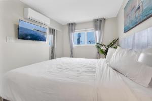 a white bedroom with a large white bed and a window at Tower 9 #6 in Oceanside
